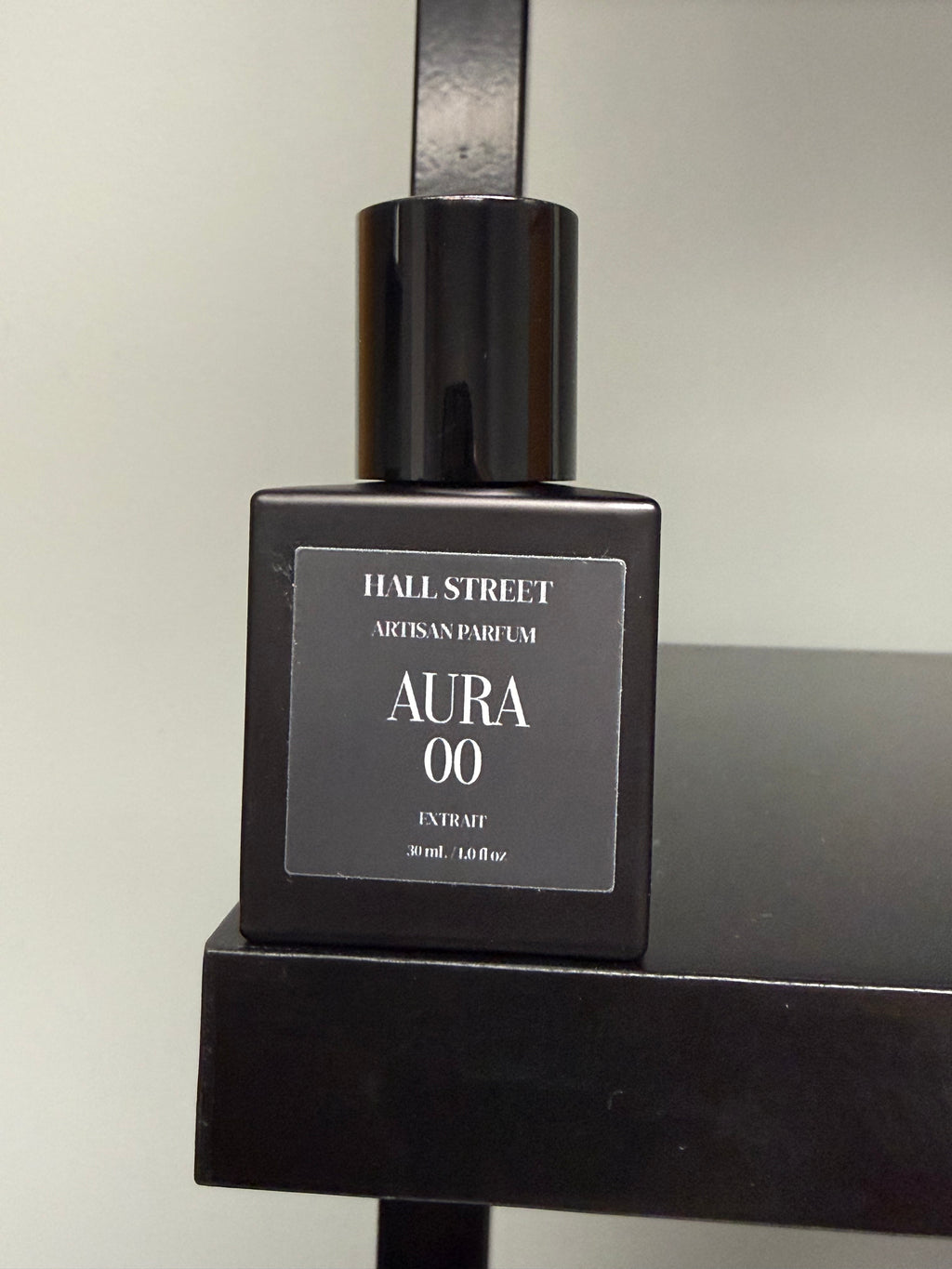 Black perfume bottle labeled  Aura00 by Hall Street  Artisan Parfum on a black surface with a neutral background