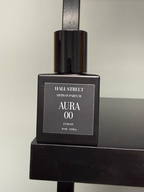 Black perfume bottle labeled  Aura00 by Hall Street  Artisan Parfum on a black surface with a neutral background